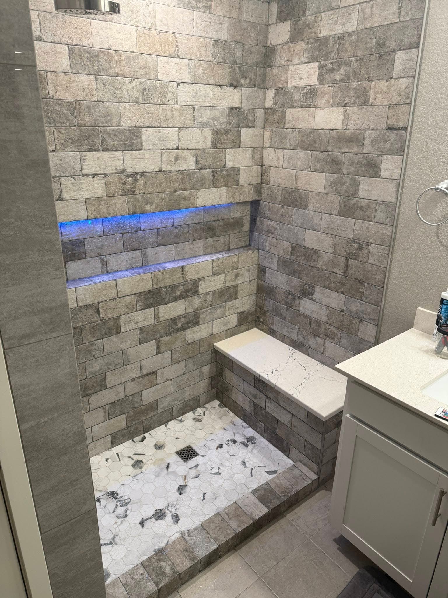 Gray brick shower with backlit niches by NOCO Tile