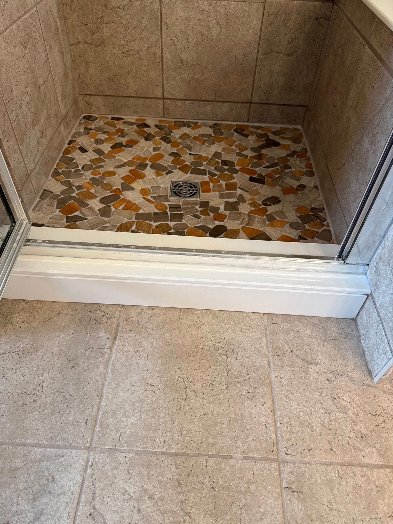 Stone mosaic shower pan with travertine surround